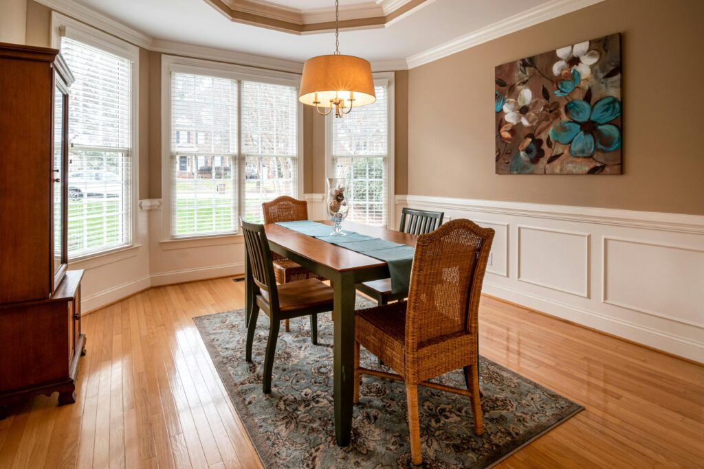 Bright dining room with wooden furniture and large windows, showcasing modern home design.